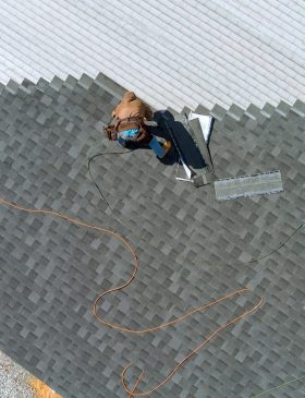 Aerial top view a asphalt shingles installation on the roof roofer is nailing asphalt shingles to roofing construction